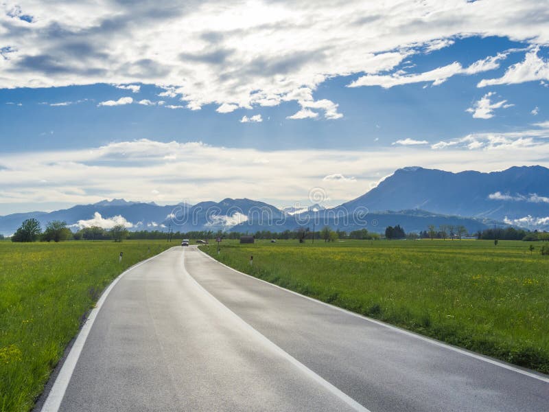 Italy countryside landscape with green grass, road and mountains