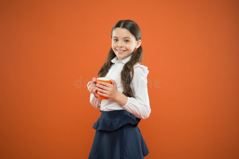 Its break time. Cute schoolgirl enjoying school break on orange background. Little girl having tea break in school stock photo Its break time. Cute schoolgirl enjoying school break on orange background. Little girl having tea break in school stock photo