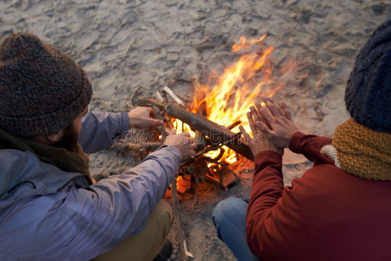 Its Cold this Morning. Two Young Men Sitting Around a Fire on the Beach