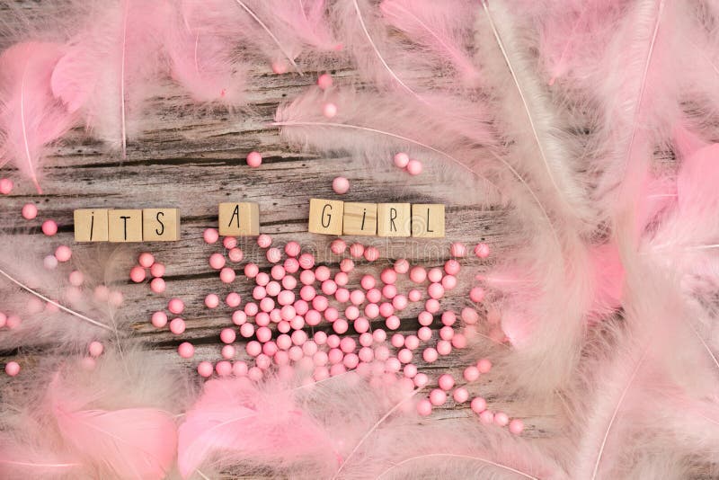 Its a Girl text on wooden background texture with pink feathers for baby invitation shower or newborn, girl announcement greeting card, top view colorful design pastel colors