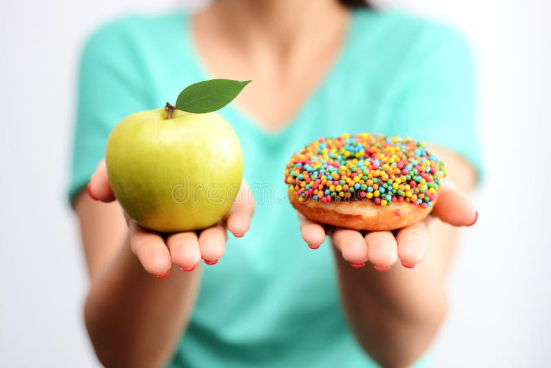 Itâ€™s moeilijk om gezond voedselconcept, met vrouwenhand te kiezen die een groene appel en een doughnut van de caloriebom houden