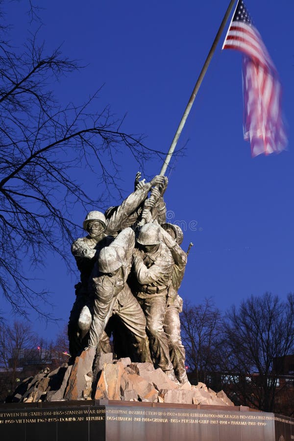 The figures of the Marines in the Iwo Jima Memorial statues erect a 60-foot bronze flagpole from which a cloth flag flies 24 hours a day. The memorial honors marines who have died defending the United States and is located near Arlington National Cemetery in Arlington Va. The figures of the Marines in the Iwo Jima Memorial statues erect a 60-foot bronze flagpole from which a cloth flag flies 24 hours a day. The memorial honors marines who have died defending the United States and is located near Arlington National Cemetery in Arlington Va.