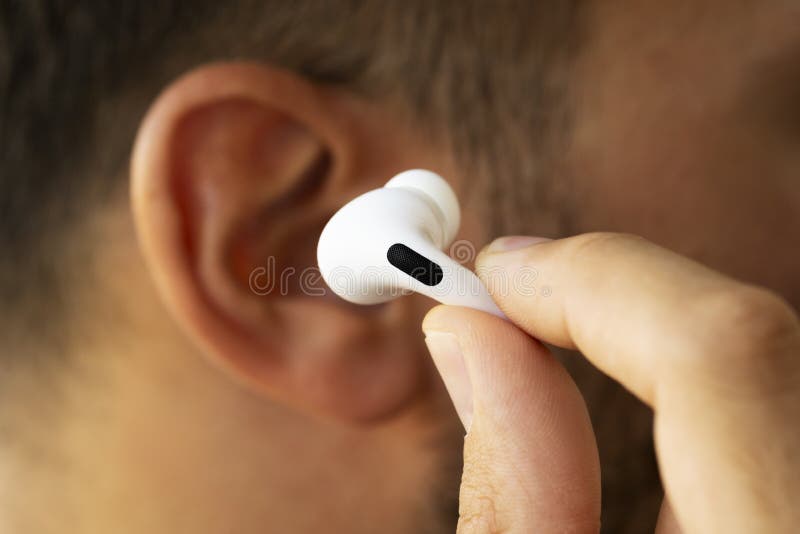 Close up shot of white colored Apple Airpods on a manâ€™s ear