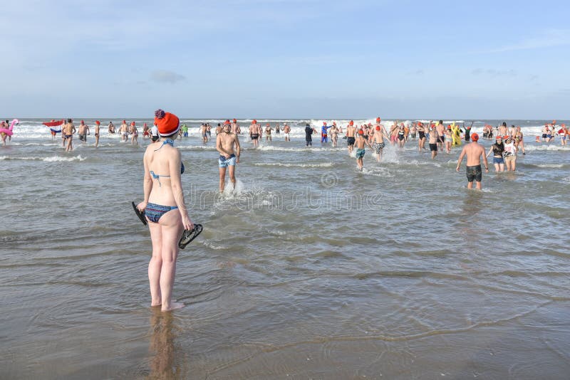 SCHEVENINGEN, 1 January 2018 - Dutch girl standing shivering in front the beach freezing water hesitates to go for her first new year dive. This is a one of the oldest Dutch tradition to get a dip in the cold water at the beginning of the new year all around the Netherlands. SCHEVENINGEN, 1 January 2018 - Dutch girl standing shivering in front the beach freezing water hesitates to go for her first new year dive. This is a one of the oldest Dutch tradition to get a dip in the cold water at the beginning of the new year all around the Netherlands