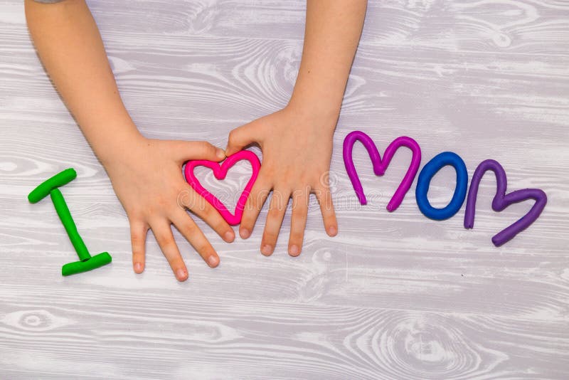 J'aime le texte de maman de la pâte à modeler avec des mains d'enfant sur le fond en bois blanc Jour de mères heureux présent fai photographie stock libre de droits J'aime le texte de maman de la pâte à modeler avec des mains d'enfant sur le fond en bois blanc Jour de mères heureux présent fai photographie stock libre de droits