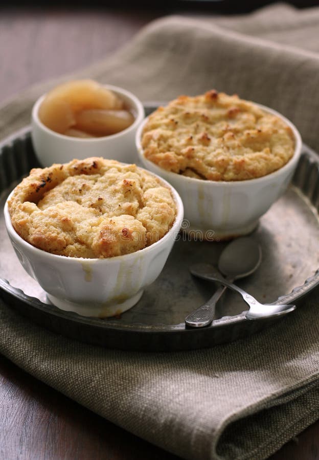 Two bowls of apple cobbler on a tin tray with apple compote. Two bowls of apple cobbler on a tin tray with apple compote