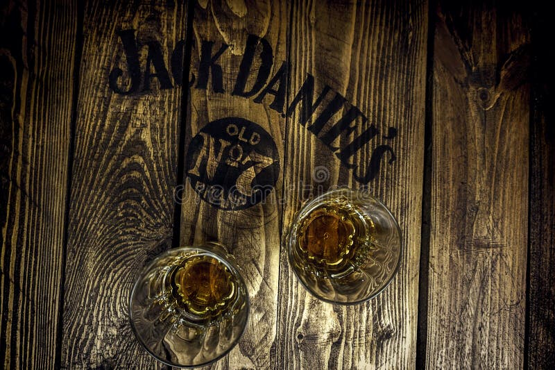 Jack Daniel`s sign on a rustic wooden pallet table with whiskey glasses