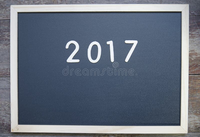 Year 2017 on a blackboard and on wood background. Year 2017 on a blackboard and on wood background