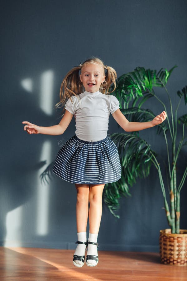 8 Jahre alte schöne kleine blonde Mädchen mit dem Haar erfasst in den Endstücken, in weißem T-Shirt, in den weißen Socken und gra stockfotos 8 Jahre alte schöne kleine blonde Mädchen mit dem Haar erfasst in den Endstücken, in weißem T-Shirt, in den weißen Socken und gra stockfotos
