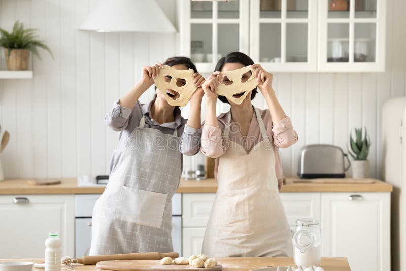 Jahrtausendalte Mutter Tochter sieht Kamera durch Teigmasken lizenzfreies stockbild