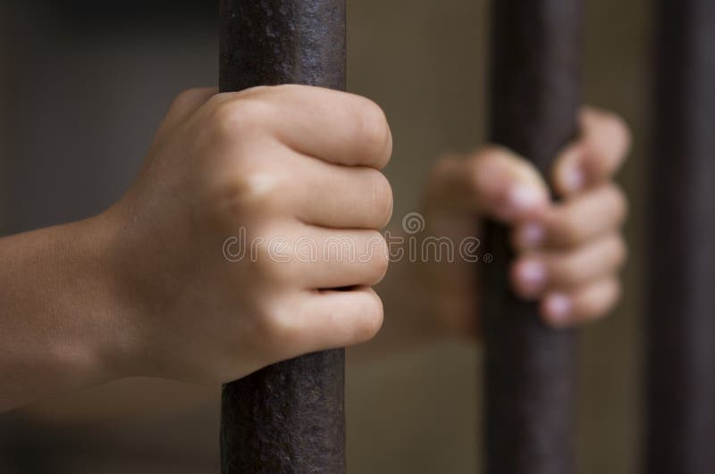 Le mani di un bambino) stringendo le sbarre di un carcere di messa a fuoco Selettiva.