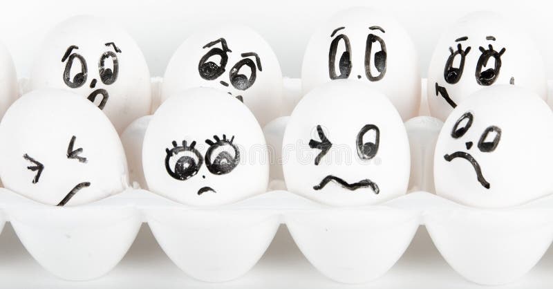 White eggs in carton with faces drawn on them with black marker. White eggs in carton with faces drawn on them with black marker.