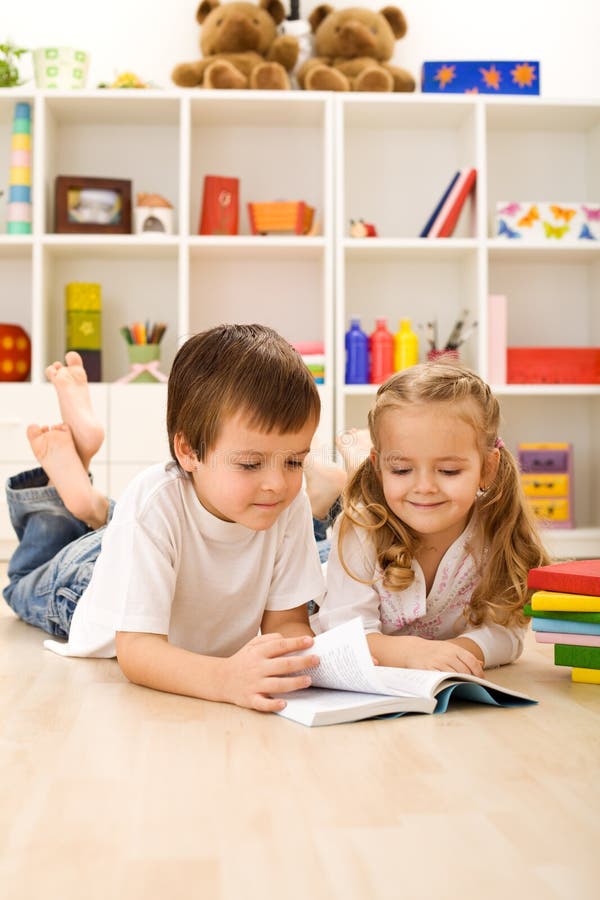 Little sister let me show you how to read - kids with books laying on the floor. Little sister let me show you how to read - kids with books laying on the floor