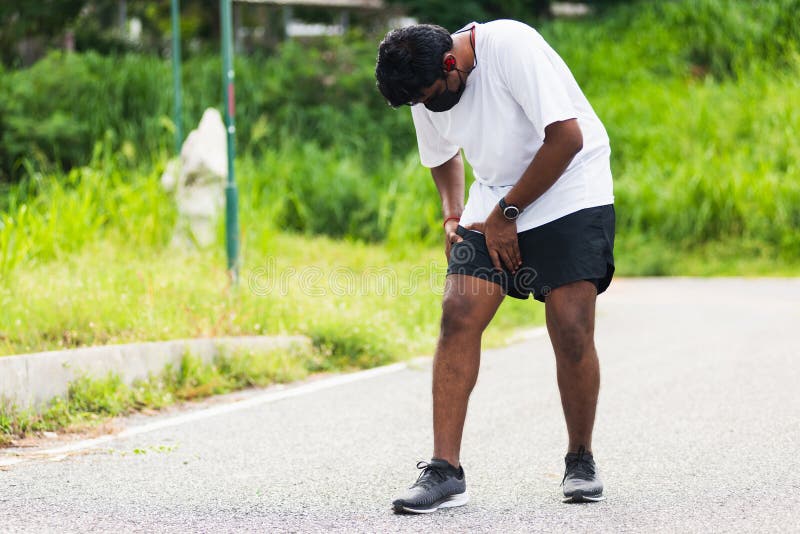 Close up Asian young sport runner black man wear watch hands joint hold leg she has thigh pain while running at the outdoor street health park, healthy exercise injury muscle from workout concept. Close up Asian young sport runner black man wear watch hands joint hold leg she has thigh pain while running at the outdoor street health park, healthy exercise injury muscle from workout concept