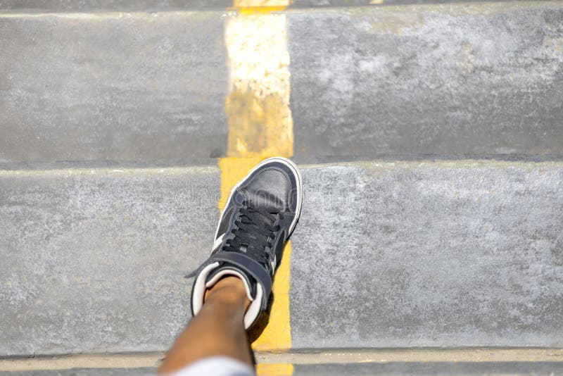 Jambes d'homme avec de longues espadrilles descendant l'escalier public avec la ligne jaune dans la ville photo stock Jambes d'homme avec de longues espadrilles descendant l'escalier public avec la ligne jaune dans la ville photo stock
