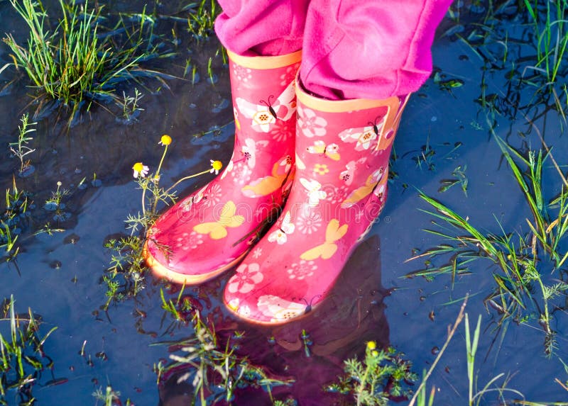 Jambes de fille d'enfant en couvre-chaussures roses à l'intérieur de magma de l'eau image stock Jambes de fille d'enfant en couvre-chaussures roses à l'intérieur de magma de l'eau image stock