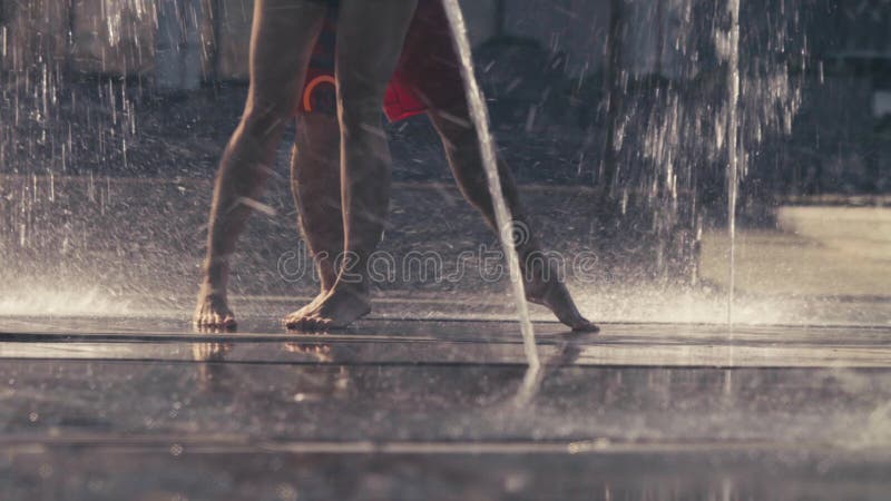 Jambes de la jeune danse de couples dans la fontaine