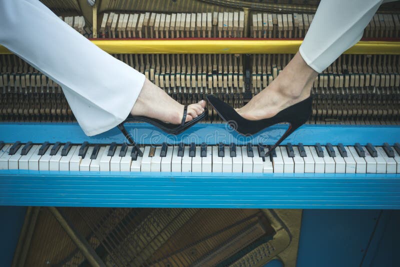 Jambes sur la couleur bleue de clavier de piano, mode photographie stock Jambes sur la couleur bleue de clavier de piano, mode photographie stock
