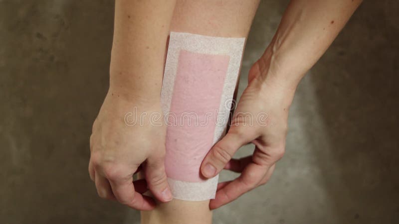 Jambes velues. femme utilisant une bande de cire d'abeille pour se raser la jambe. procédure de dépilation avec fermeture de cire. banque de vidéos