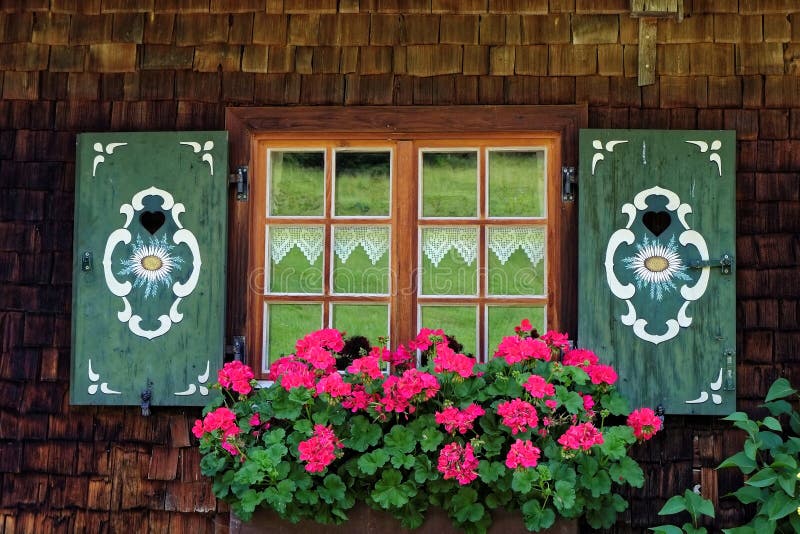 Janela antiga com contraventana pintada e floreira com petúnias foto de stock