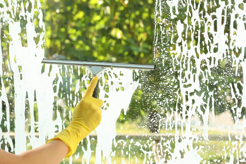 Janitor cleaning window with squeegee indoors