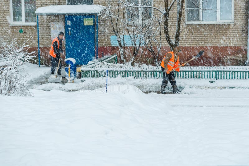 janitor δύο ατόμων στα φτυάρια φορμών μια πορεία μπροστά από το σπίτι από το χιόνι κατά τη διάρκεια χιονοπτώσεων στοκ φωτογραφία με δικαίωμα ελεύθερης χρήσης janitor δύο ατόμων στα φτυάρια φορμών μια πορεία μπροστά από το σπίτι από το χιόνι κατά τη διάρκεια χιονοπτώσεων στοκ φωτογραφία με δικαίωμα ελεύθερης χρήσης