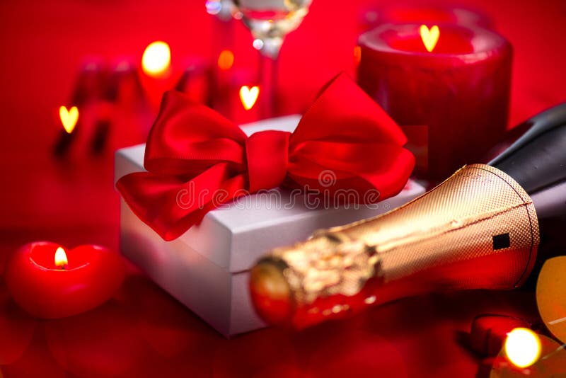 Jantar romântico do dia de Valentim data Champagne, velas e caixa de presente sobre o fundo do vermelho do feriado foto de stock Jantar romântico do dia de Valentim data Champagne, velas e caixa de presente sobre o fundo do vermelho do feriado foto de stock