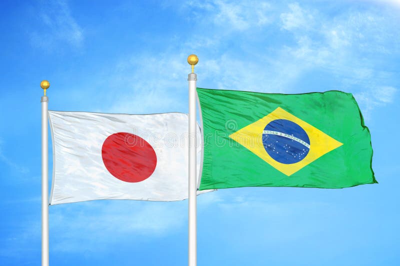 Brazil and Japan Two Flags on Flagpoles and Blue Cloudy Sky Stock Photo