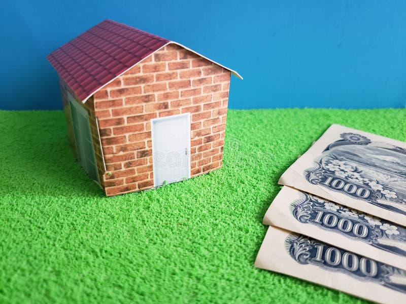 japanese banknotes and figure of a house on green surface and blue background stock image japanese banknotes and figure of a house on green surface and blue background stock image