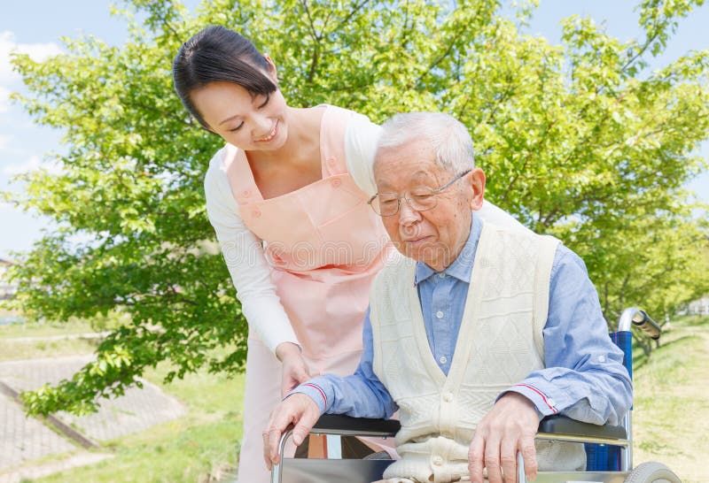 Asiatico senior uomini seduti su una sedia a rotelle con il caregiver.