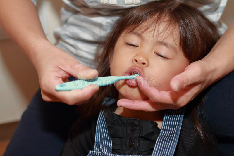 Japanese Girl Whose Teeth Are Brushed By Her Mom Stock Image