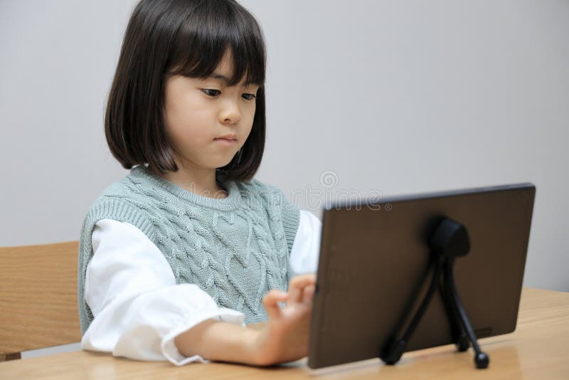 Japanese Student Girl Using a Tablet PC in Dining Room Stock Photo