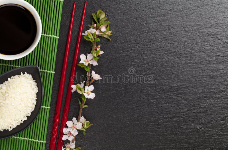 Japanese sushi chopsticks, soy sauce bowl, rice and sakura blossom