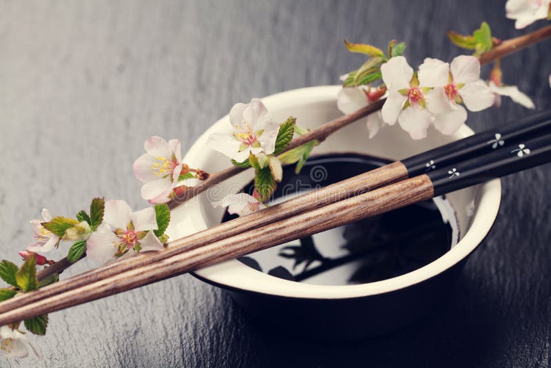 Japanese sushi chopsticks, soy sauce bowl and sakura blossom