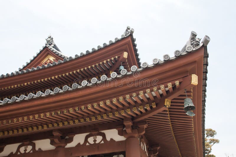 Japanese temple roof against blue sky.