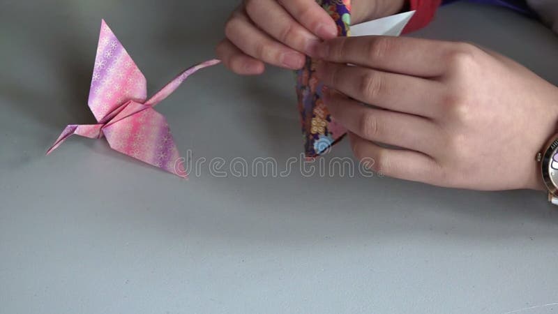 Japanische Frauenhände, die Origami des japanischen Papiers falten