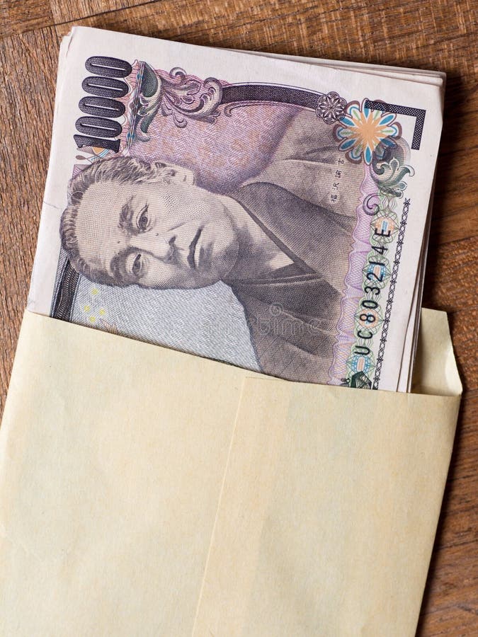 Japanese 10000 yen bill in the envelope on the wooden table. Japanese 10000 yen bill in the envelope on the wooden table