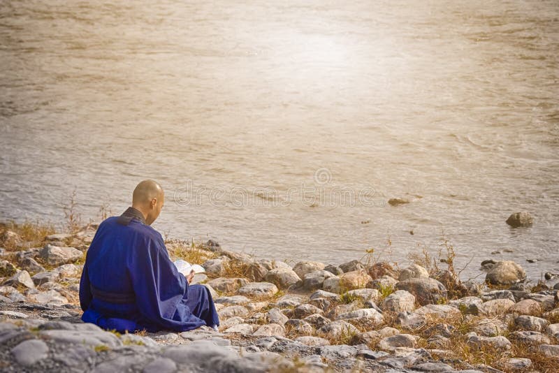 Japanese Male Monk in Blue Robe Reading Book on River Bank.Horizontal Image. Japanese Male Monk in Blue Robe Reading Book on River Bank.Horizontal Image