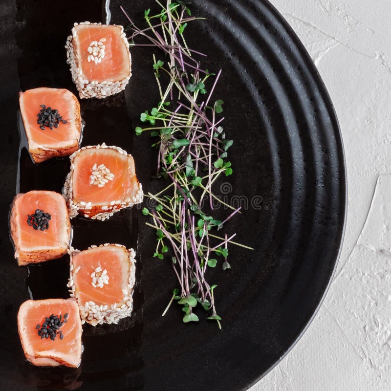 Japoński łososiowy Tataki z sezamem i flancami świezi ziele Na czarnym glina talerzu Makro- fotografia, zakończenie zdjęcie stock Japoński łososiowy Tataki z sezamem i flancami świezi ziele Na czarnym glina talerzu Makro- fotografia, zakończenie zdjęcie stock