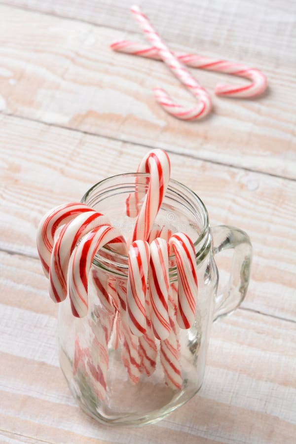 A jar of candy canes on a wood table. High angle shot with shallow depth of field.