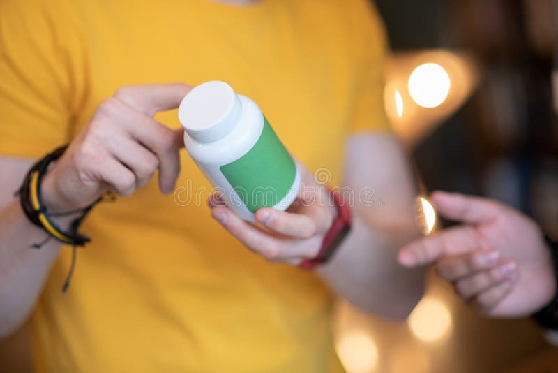 Jar with pills. Close up picture of a man holding a jar with pills