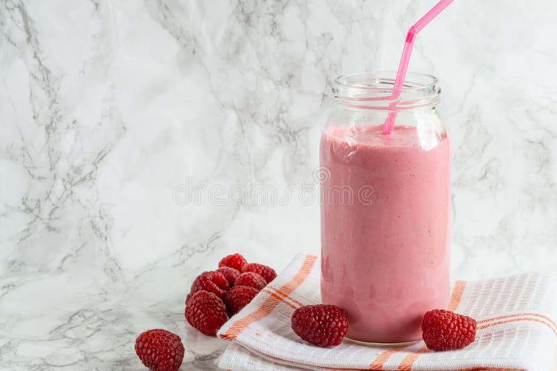 Jar with rasberry smoothie and fresh rasberry on tawel on white background