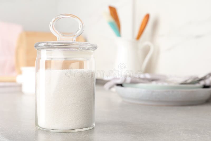 Jar with white sugar on grey table