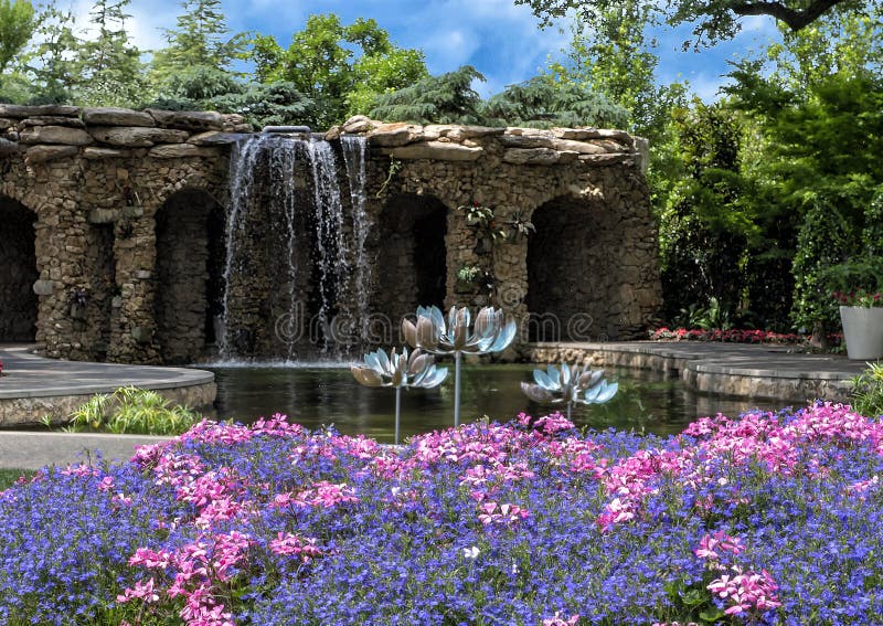 Pictured is a portion of the Lay Family Garden in the Dallas Arboretum. In the backgound a 12-foot waterfall cascades over a stone grotto into a large lagoon. Three wind sculptures by Lyman Whitaker stand in the lagoon. Whitaker is the world`s most recognized creator of kinetic art, and his copper wind spinners are mesmerizing juxtaposed with the beautiful gardens. In the foreground is a colorful bed of blue lobelia and pink geraniums. The sixty-six acre botanical garden opened in 1984. It is located in East Dallas on the shore of White Rock Lake. It has nineteen named gardens. Pictured is a portion of the Lay Family Garden in the Dallas Arboretum. In the backgound a 12-foot waterfall cascades over a stone grotto into a large lagoon. Three wind sculptures by Lyman Whitaker stand in the lagoon. Whitaker is the world`s most recognized creator of kinetic art, and his copper wind spinners are mesmerizing juxtaposed with the beautiful gardens. In the foreground is a colorful bed of blue lobelia and pink geraniums. The sixty-six acre botanical garden opened in 1984. It is located in East Dallas on the shore of White Rock Lake. It has nineteen named gardens.