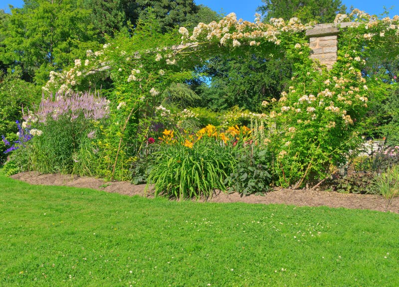 Sunny summer garden with green lawn and stone arc. Sunny summer garden with green lawn and stone arc.