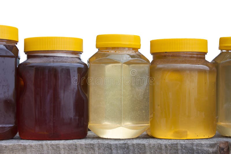 Jars with yellow plastic lids with different types of honey - buckwheat, linden royalty free stock photo