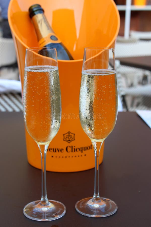 Jaskrawa pomarańczowa lodowego wiadra mienia butelka Veuve Clicquot szampański Błękitny Kurny piwo i wino Uprawiamy ogródek, Sara zdjęcie stock Jaskrawa pomarańczowa lodowego wiadra mienia butelka Veuve Clicquot szampański Błękitny Kurny piwo i wino Uprawiamy ogródek, Sara zdjęcie stock