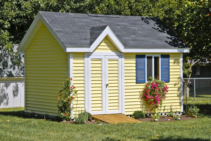 Storage shed in a yard with green grass flowers. Storage shed in a yard with green grass flowers