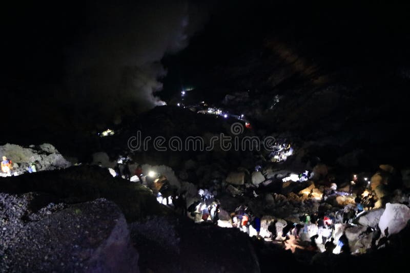 印尼爪哇岛伊真火山 - 2024年2月4日：人们在夜间步行前往火山火山口的蓝色火焰 免版税库存照片