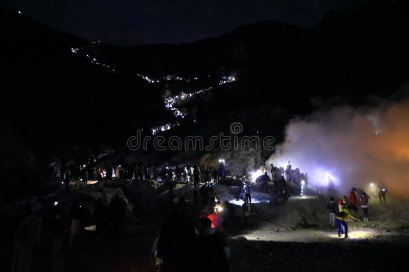 印尼爪哇岛伊根火山 - 2024年2月4日：人们在夜间行走，前往火山火山口的蓝色火焰 图库摄影
